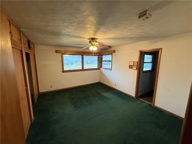 carpeted empty room with ceiling fan and a textured ceiling