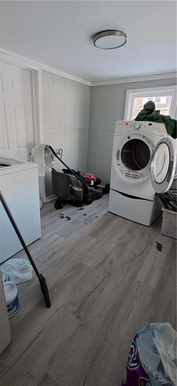 laundry room featuring washer and clothes dryer, hardwood / wood-style floors, and crown molding