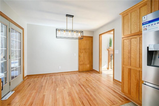 unfurnished dining area featuring an inviting chandelier and light wood-type flooring