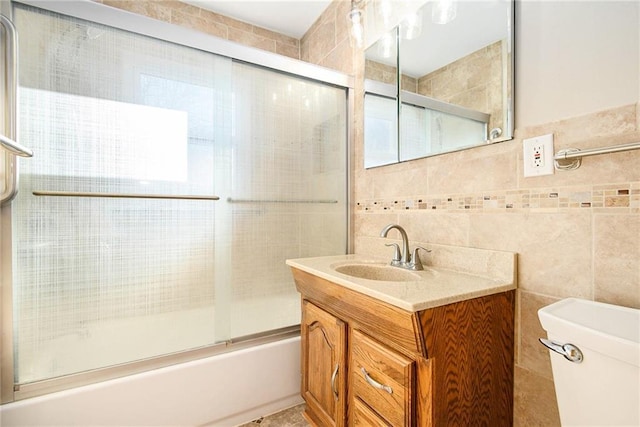 full bathroom with tile walls, vanity, enclosed tub / shower combo, and toilet