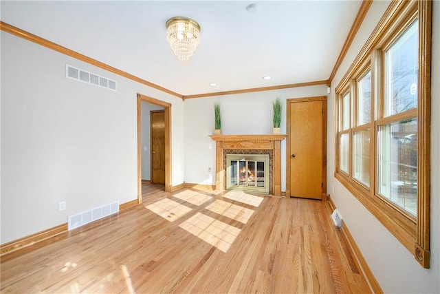 unfurnished living room featuring crown molding, a fireplace, a chandelier, and light wood-type flooring