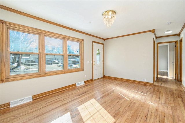 empty room featuring crown molding, light hardwood / wood-style flooring, and a notable chandelier