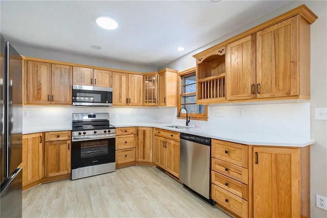 kitchen featuring stainless steel appliances, light hardwood / wood-style floors, sink, and backsplash