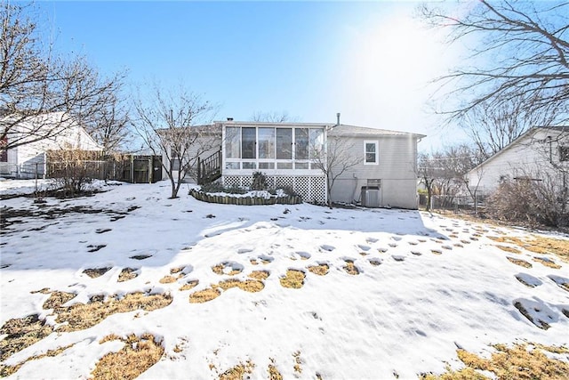 snow covered rear of property featuring a sunroom and central air condition unit