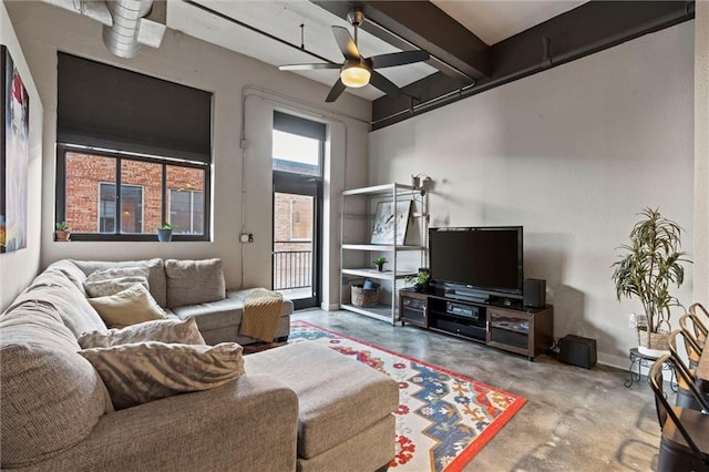 living room featuring beamed ceiling, concrete flooring, and ceiling fan