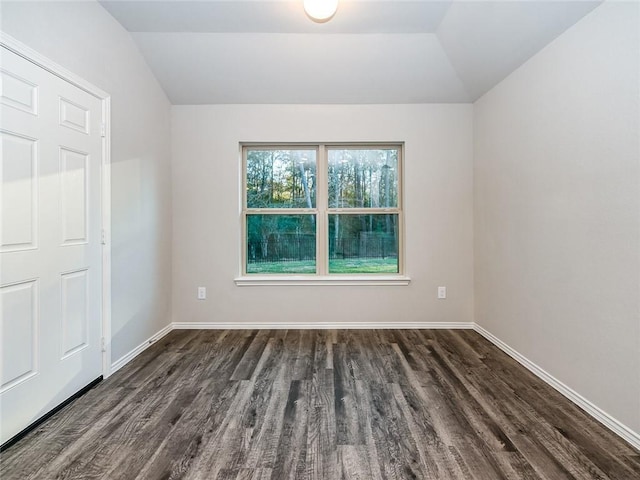 empty room featuring vaulted ceiling and dark hardwood / wood-style floors