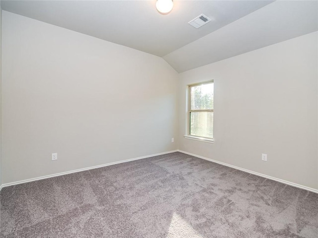 carpeted empty room with vaulted ceiling