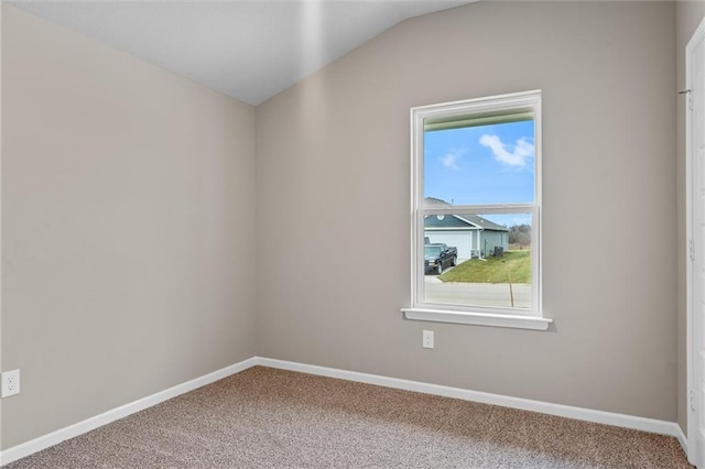 carpeted empty room featuring vaulted ceiling