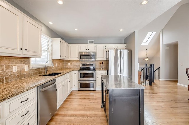 kitchen with stainless steel appliances, sink, a kitchen island, and white cabinets