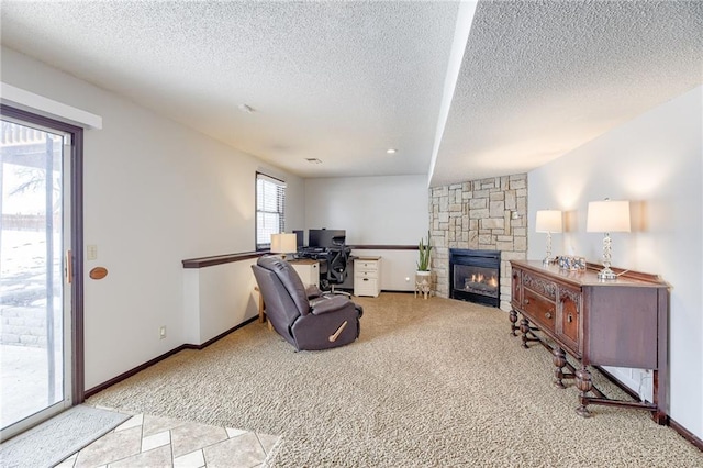 carpeted living room with a stone fireplace and a textured ceiling