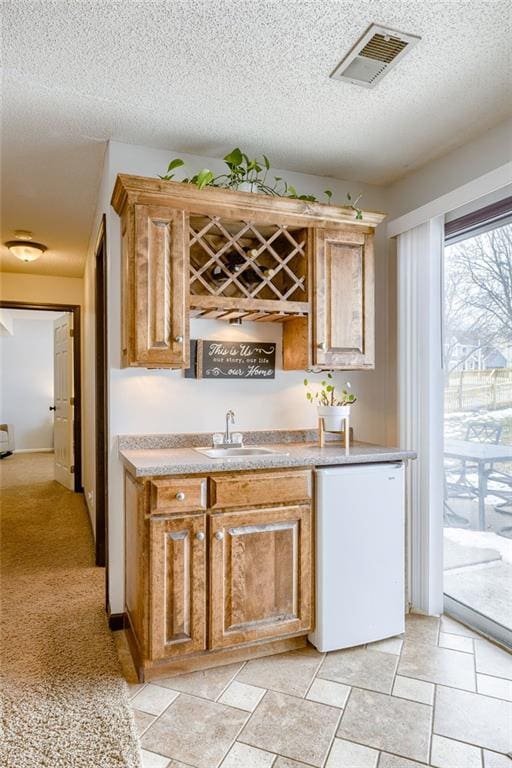 bar featuring dishwasher, sink, and a textured ceiling