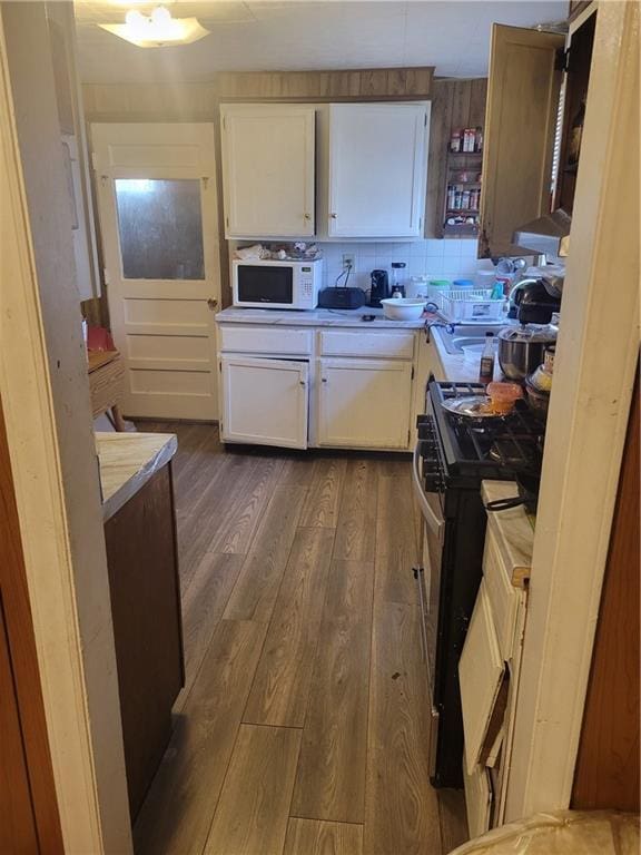 kitchen featuring sink, dark wood-type flooring, tasteful backsplash, gas range oven, and white cabinets