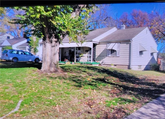 view of front facade featuring a chimney and a front lawn