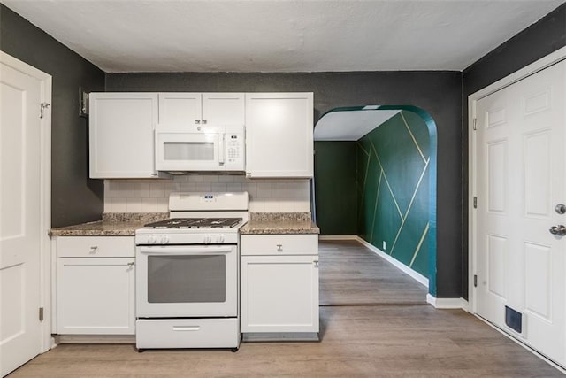 kitchen with white appliances, light hardwood / wood-style flooring, and white cabinets