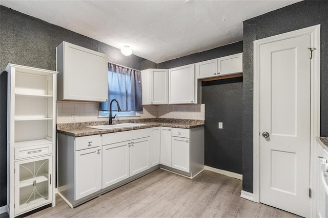 kitchen featuring tasteful backsplash, sink, white cabinets, and light wood-type flooring