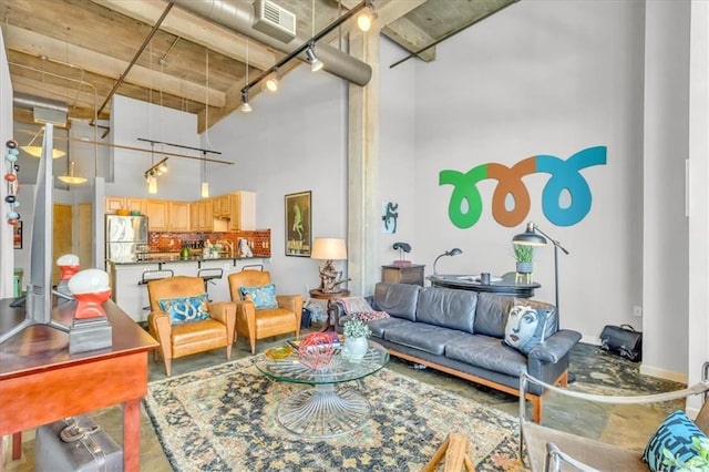 living room featuring concrete floors, a high ceiling, visible vents, and track lighting