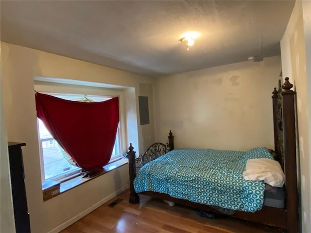 bedroom with hardwood / wood-style flooring and electric panel