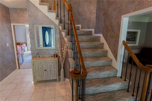 stairway with crown molding and tile patterned flooring