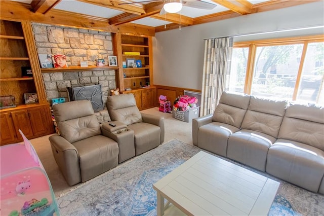 living room featuring built in shelves, a stone fireplace, coffered ceiling, and beamed ceiling