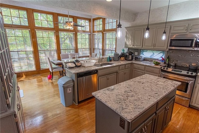 kitchen featuring kitchen peninsula, a kitchen island, pendant lighting, and stainless steel appliances