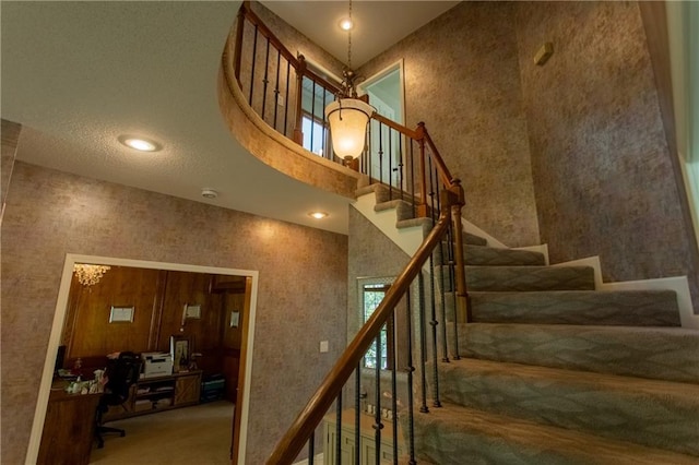 stairway with carpet floors, a high ceiling, and a notable chandelier