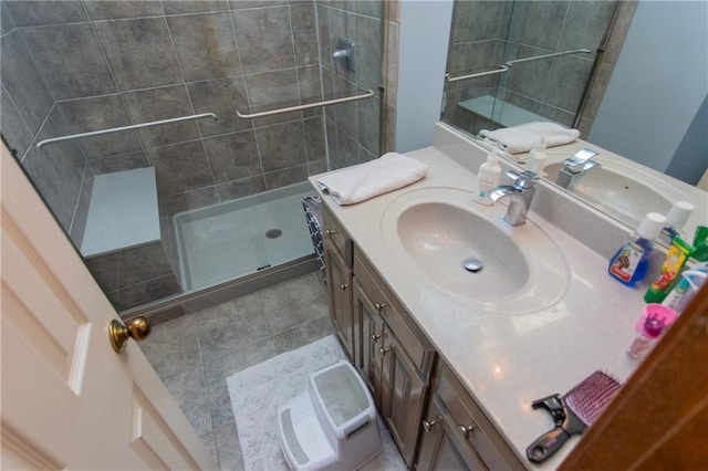 bathroom with a shower with shower door, tile patterned floors, and vanity