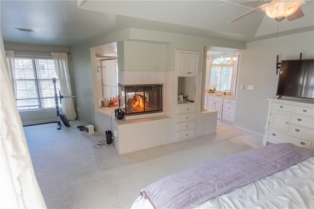 carpeted bedroom with ceiling fan, a fireplace, and a tray ceiling