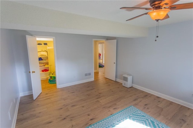 bedroom with a walk in closet, ceiling fan, light wood-type flooring, and a closet