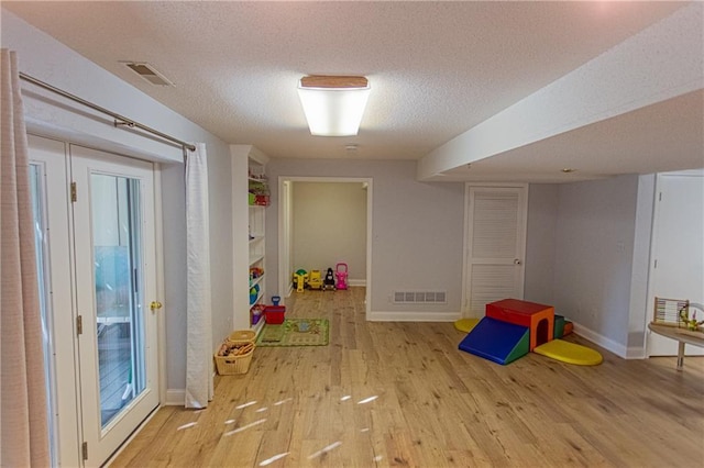 game room featuring a textured ceiling and light hardwood / wood-style flooring