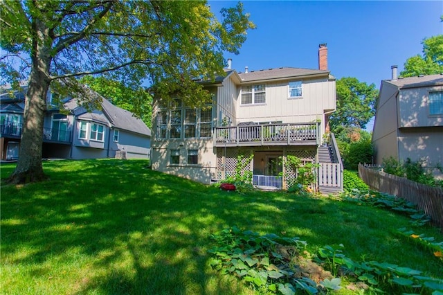 back of property with a wooden deck, a sunroom, and a yard