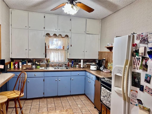 kitchen featuring white fridge with ice dispenser, a textured ceiling, blue cabinetry, sink, and stove