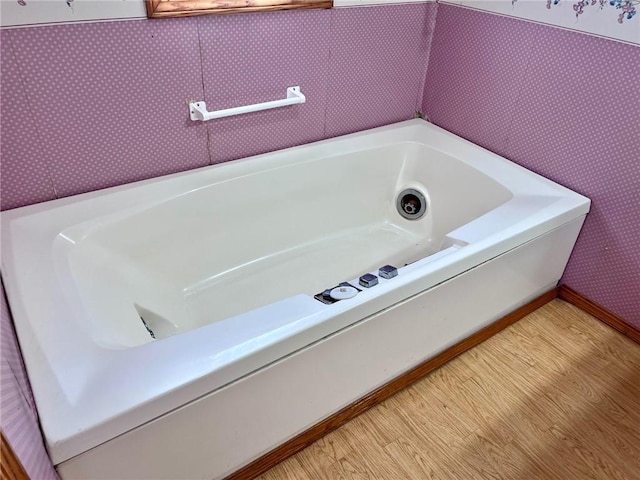 bathroom with hardwood / wood-style flooring and a tub to relax in