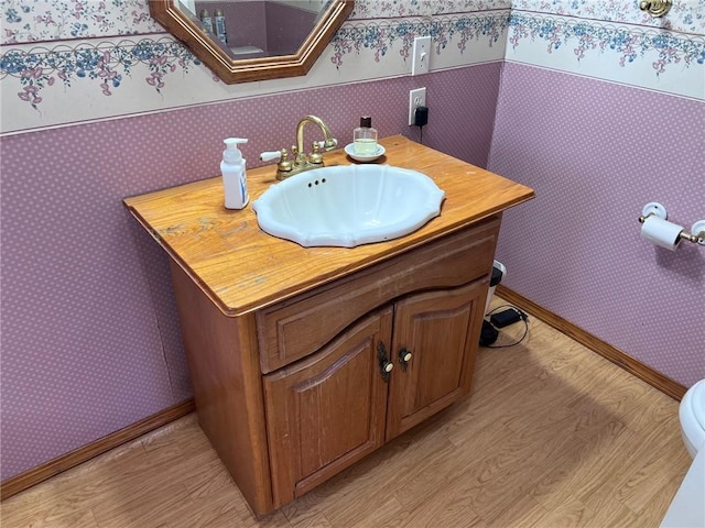 bathroom with hardwood / wood-style flooring, toilet, and vanity