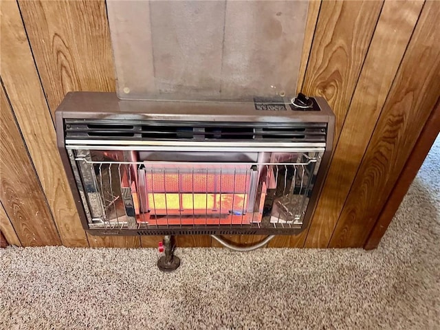 room details featuring carpet, heating unit, and wood walls