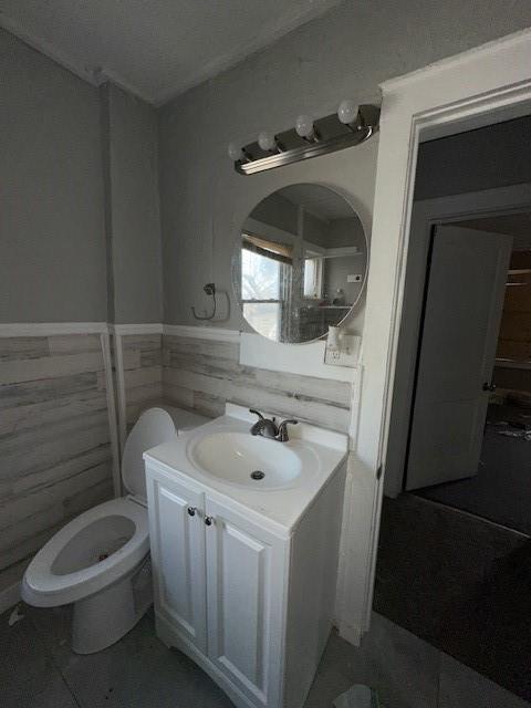 bathroom with vanity, toilet, and tile walls