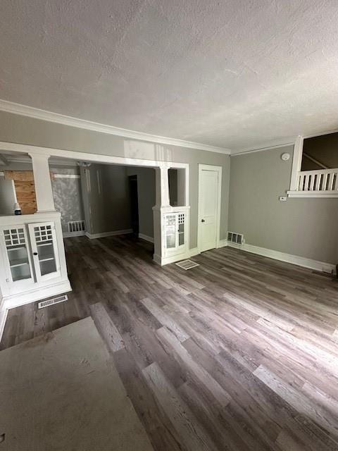 3920 S Benton Ave, Kansas City, MO 64130 - unfurnished living room featuring a textured ceiling, crown molding, wood finished floors, and baseboards