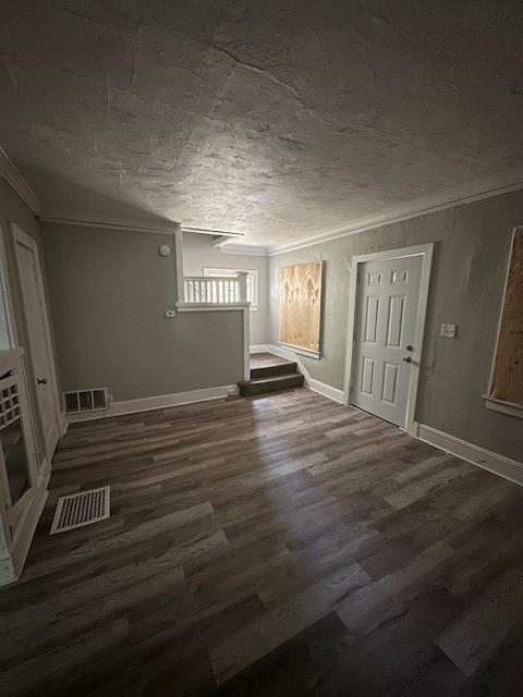 3920 S Benton Ave, Kansas City, MO 64130 - unfurnished living room with ornamental molding, wood finished floors, baseboards, and a textured ceiling