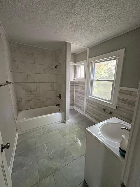 3920 S Benton Ave, Kansas City, MO 64130 - bathroom featuring  shower combination, a textured ceiling, vanity, and marble look tile flooring