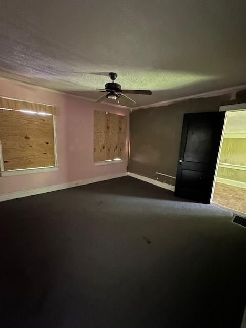 3920 S Benton Ave, Kansas City, MO 64130 - unfurnished living room featuring a ceiling fan, a textured ceiling, and baseboards