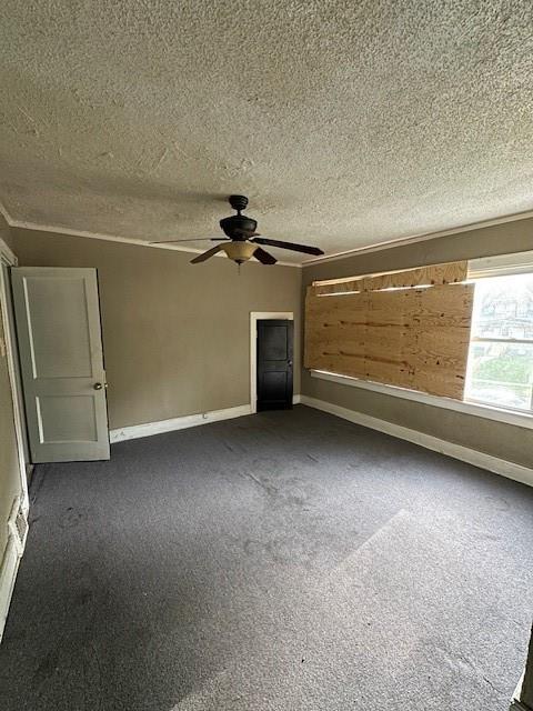 3920 S Benton Ave, Kansas City, MO 64130 - unfurnished living room with dark carpet, ceiling fan, a textured ceiling, and baseboards