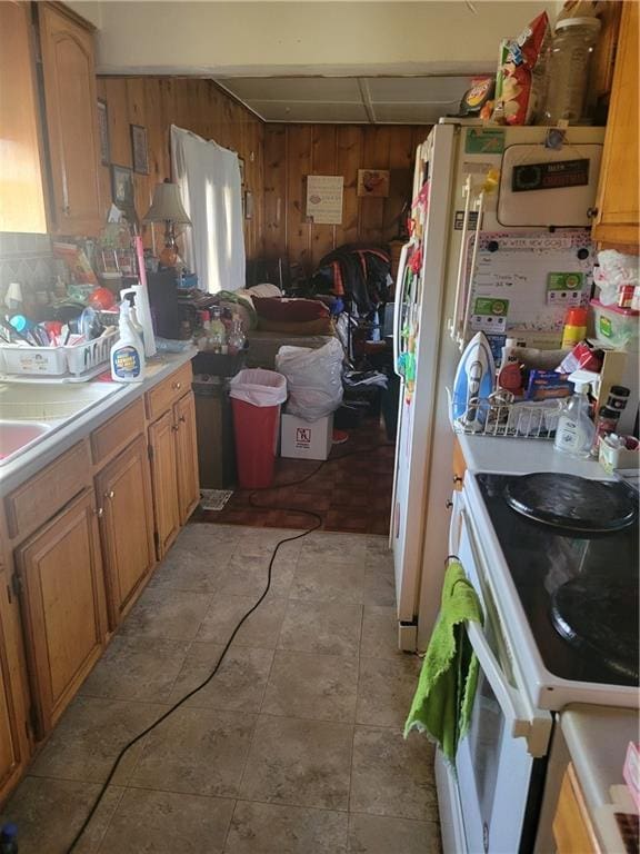 kitchen with light tile patterned floors, white appliances, and wood walls