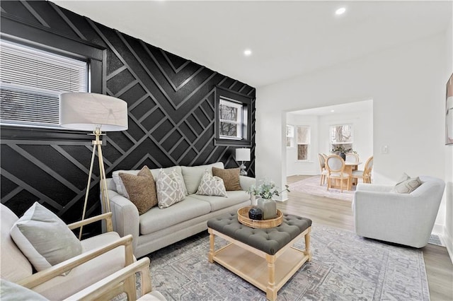 living room with an accent wall, wood finished floors, and recessed lighting