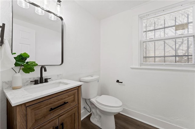 bathroom with toilet, baseboards, wood finished floors, and vanity