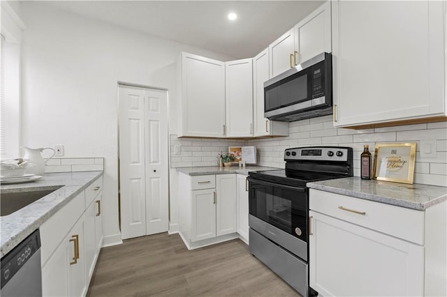 kitchen featuring white cabinetry, light stone counters, stainless steel appliances, and backsplash