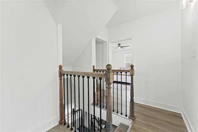 stairway featuring a textured ceiling, baseboards, and wood finished floors