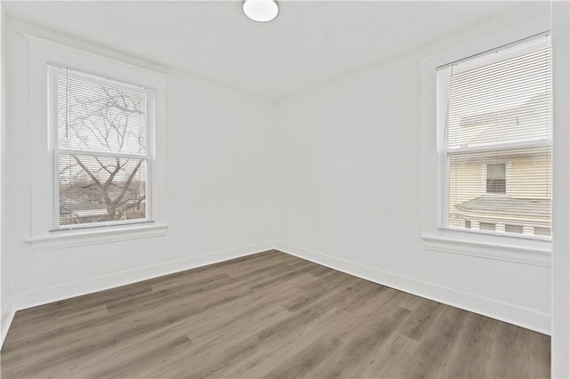 unfurnished room with plenty of natural light, baseboards, and wood finished floors