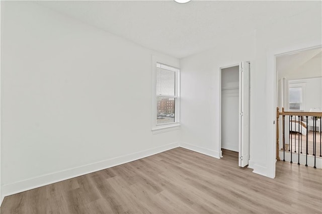 unfurnished bedroom with light wood finished floors, baseboards, and a closet