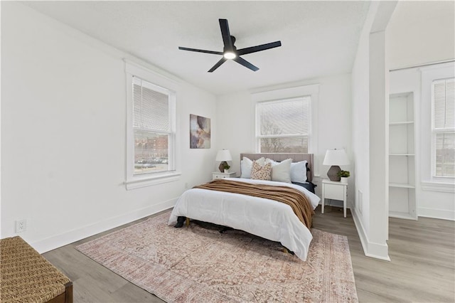 bedroom featuring light wood-style floors, multiple windows, and baseboards