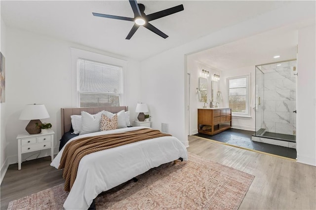 bedroom featuring a ceiling fan, connected bathroom, baseboards, and wood finished floors