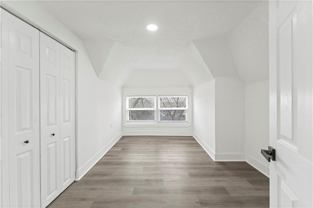 bonus room with vaulted ceiling, a textured ceiling, baseboards, and wood finished floors